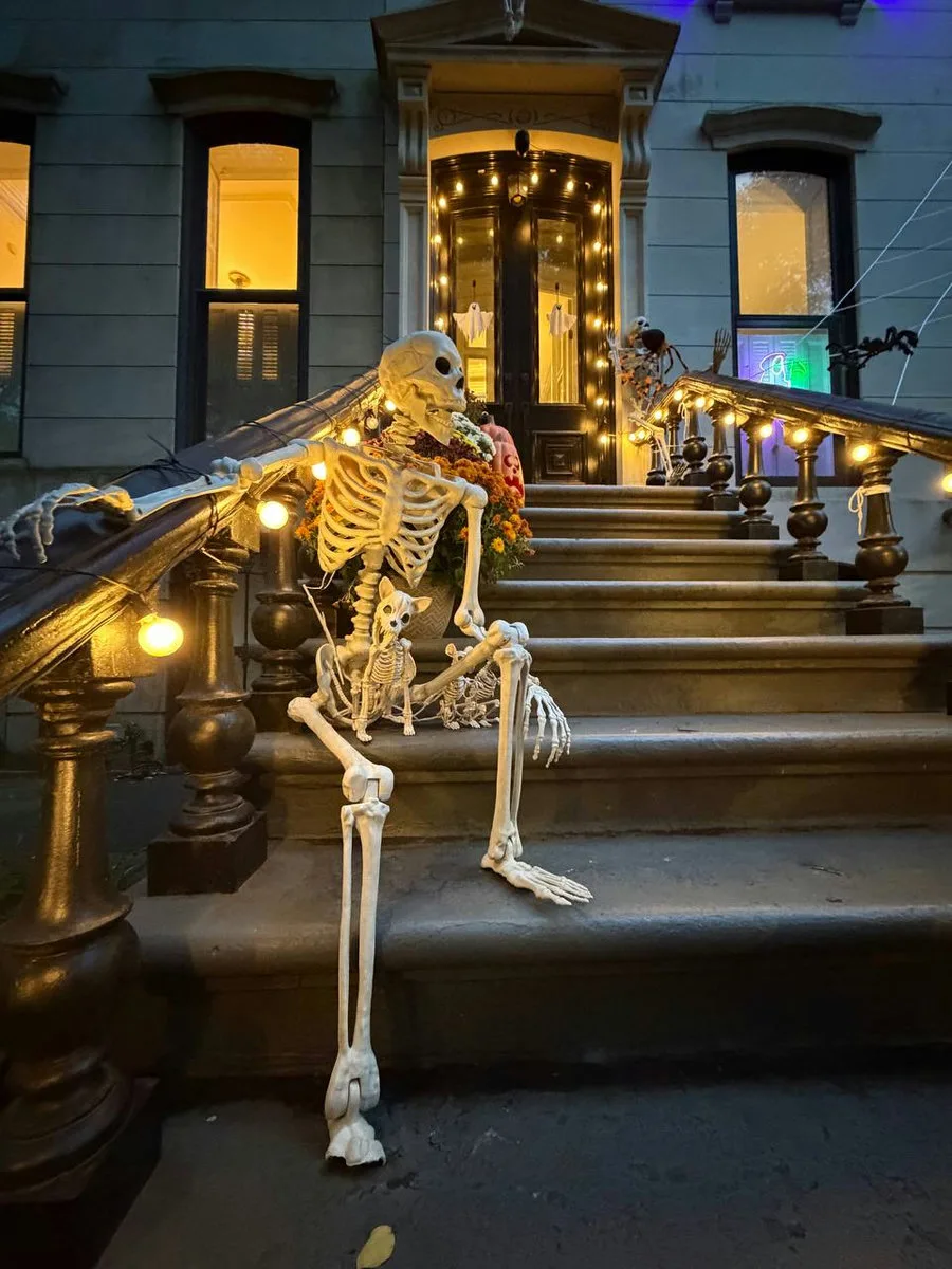 A giant skeleton draped over a brownstone stoop railing